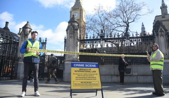 Two peope in Hi-Vis hold 'Crime scene' tape in front of a 'Crime scene' sign outside Parliament