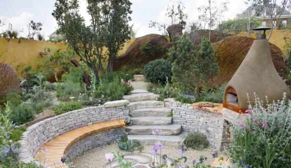 Landscape photo of our garden at Chelsea, with a bread oven and seating area