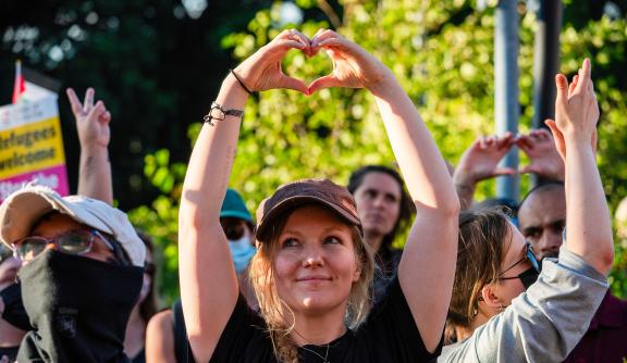 A protester makes a heart with her hands to show her love to asylum seekers