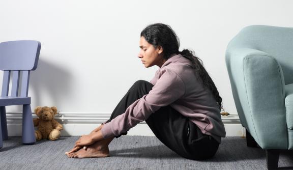 Young South Asian woman sitting on the floor looking sad