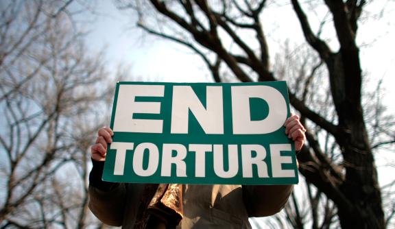 A person holds a sign that reads 'End torture'
