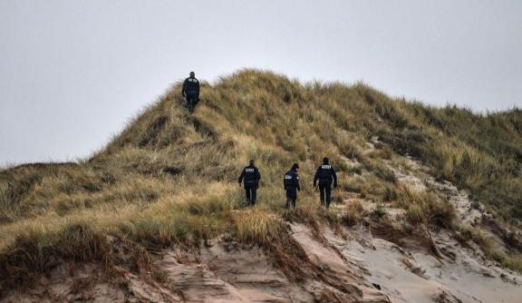 Police officers patrol on the dunes of a beach